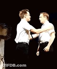 Two Men Are Standing Next To Each Other On A Stage And Hugging Each Other . GIF