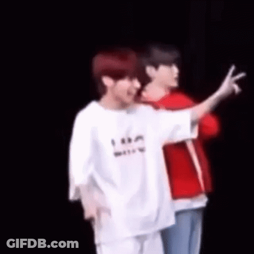 Two Men Are Standing Next To Each Other On A Stage And One Of Them Is Giving The Peace Sign . GIF
