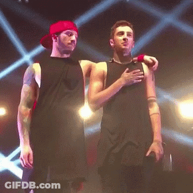 Two Men Are Standing Next To Each Other On A Stage And One Of Them Is Hugging The Other . GIF