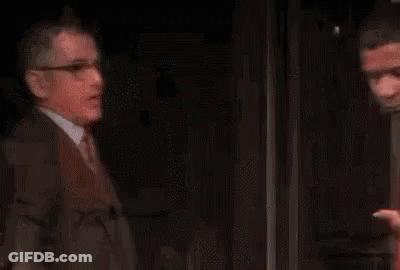 Two Men Are Standing Next To Each Other On A Stage In A Dark Room . GIF