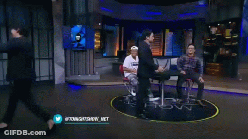 Two Men Are Standing Next To Each Other On A Stage . GIF