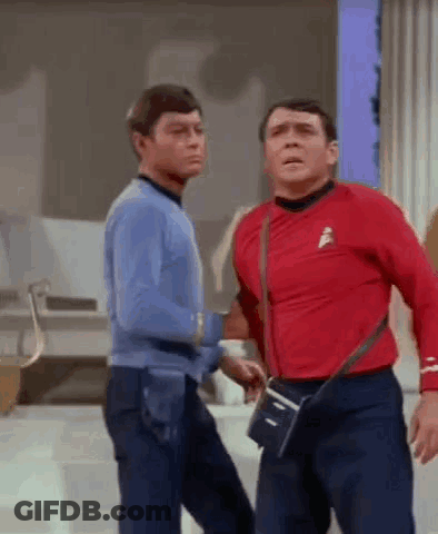 Two Men Are Standing Next To Each Other On A Stage . One Of The Men Is Wearing A Red Shirt . GIF