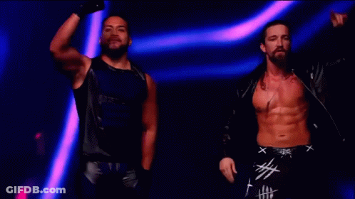 Two Men Are Standing Next To Each Other On A Stage . GIF