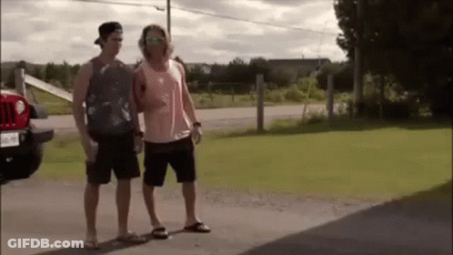 Two Men Are Standing Next To Each Other On The Side Of A Road In Front Of A Jeep . GIF