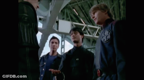Two Men Are Standing Next To Each Other With One Wearing A Watch That Has A Red Circle On It GIF