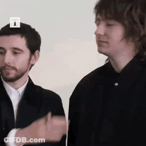 Two Men Are Standing Next To Each Other With The Letter T On The Top GIF