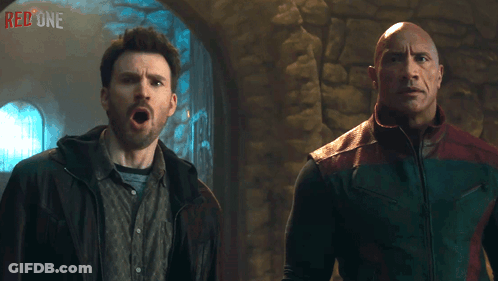 Two Men Are Standing Next To Each Other With The Word Red One On The Wall Behind Them GIF