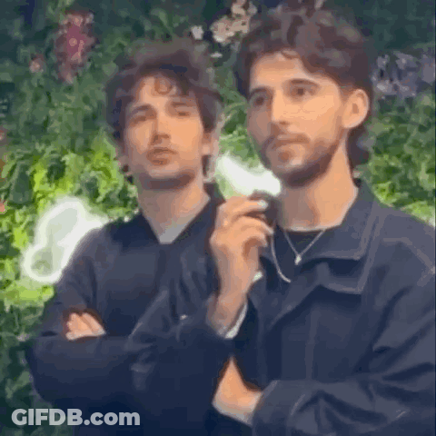 Two Men Are Standing Next To Each Other With Their Arms Crossed And Looking At Something . GIF