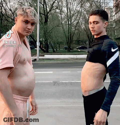Two Men Are Standing Next To Each Other With Their Stomachs Exposed . GIF
