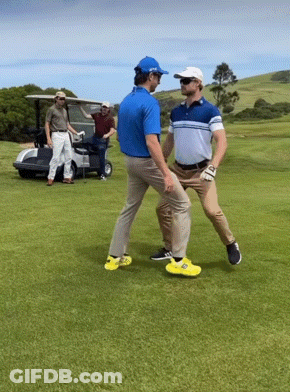 Two Men Are Standing On A Golf Course And One Is Wearing Yellow Shoes GIF