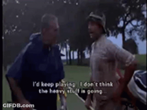 Two Men Are Standing On A Golf Course Talking To Each Other GIF