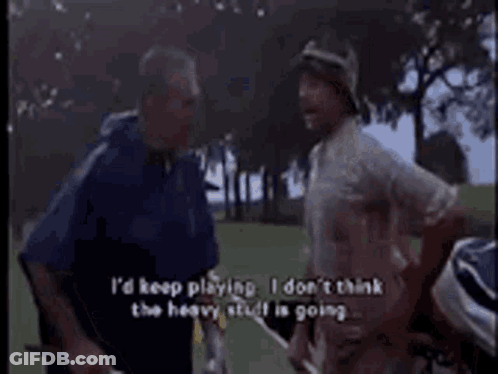 Two Men Are Standing On A Golf Course Talking To Each Other . One Of The Men Is Holding A Golf Club . GIF
