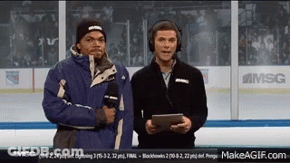 Two Men Are Standing On A Hockey Rink Talking Into Microphones . GIF