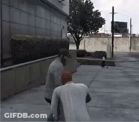 Two Men Are Standing On A Sidewalk In Front Of A Building And A Tree GIF