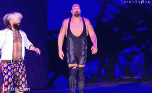 Two Men Are Standing On A Stage In Front Of A Blue Background . One Of The Men Is Wearing A Black Wrestling Outfit . GIF