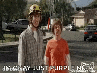Two Men Are Standing On A Street And One Of Them Is Wearing A Helmet And The Other Is Wearing An Orange Shirt GIF