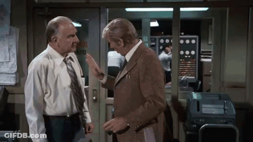 Two Men Are Talking In Front Of A Door That Says Rio GIF