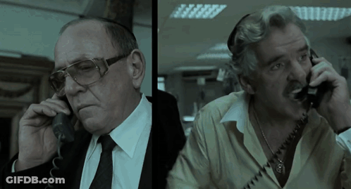 Two Men Are Talking On Their Phones And One Has Glasses On GIF