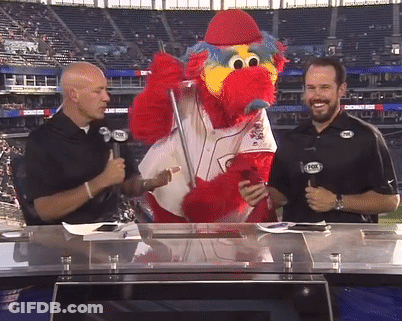 Two Men Are Talking To A Mascot Wearing A Fox Logo GIF