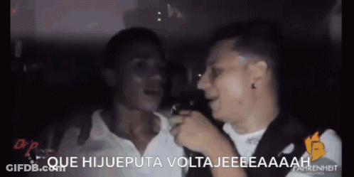 Two Men Are Talking To Each Other In A Dark Room And The Words Que Hijueputa Voltajeeeaaaah Are On The Screen GIF