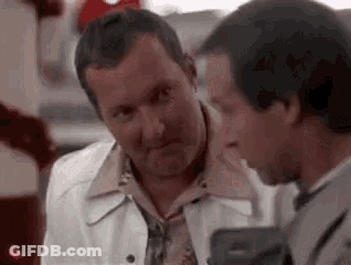 Two Men Are Talking To Each Other In A Restaurant And One Of Them Is Holding A Gun . GIF