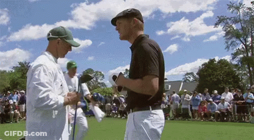 Two Men Are Talking To Each Other On A Golf Course GIF