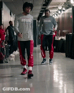 Two Men Are Walking Down A Hallway And One Has A Shirt That Says Reebok On It GIF