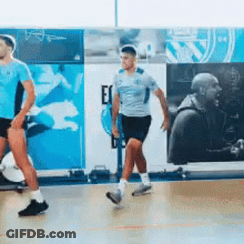 Two Men Are Walking On A Basketball Court In Front Of A Wall That Says Ec On It GIF