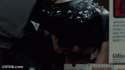 Two Men Are Working In A Gun Shop With An Exit Sign Above Them GIF