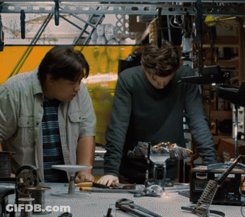 Two Men Are Working On A Project In A Workshop With A Soldering Iron That Says ' A ' On It GIF