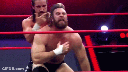Two Men Are Wrestling In A Ring And One Of Them Is Wearing A Bandage On His Chest . GIF