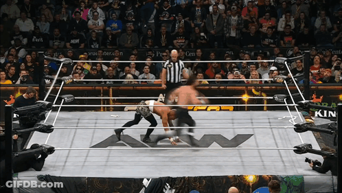 Two Men Are Wrestling In A Ring That Has A Kin Logo On The Floor GIF