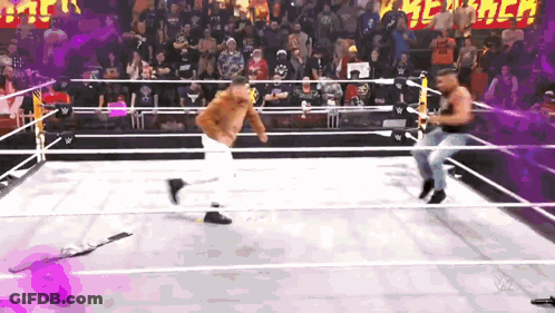 Two Men Are Wrestling In A Ring With A Crowd In The Background GIF