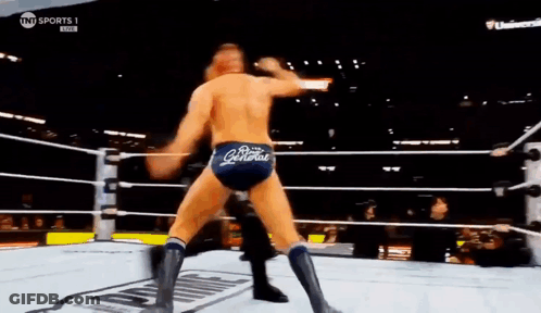 Two Men Are Wrestling In A Ring With A Referee In The Background . GIF