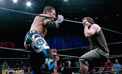 Two Men Are Wrestling In A Ring With One Wearing A Pair Of Shorts That Say J.j. GIF