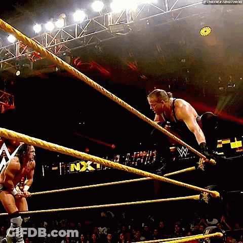 Two Men Are Wrestling In A Wrestling Ring And One Of Them Is Jumping Over Ropes . GIF