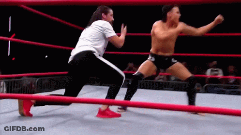 Two Men Are Wrestling In A Wrestling Ring . GIF