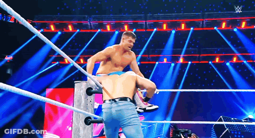 Two Men Are Wrestling In A Wrestling Ring On A Stage With A Lot Of Lights . GIF