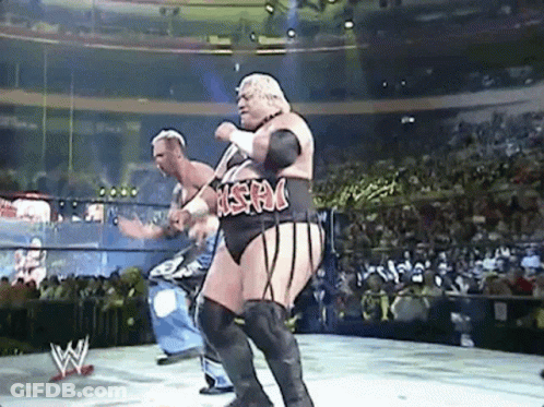Two Men Are Wrestling In A Wrestling Ring With A Crowd In The Background . GIF