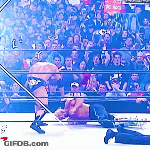 Two Men Are Wrestling In A Wrestling Ring With A Crowd Watching . GIF