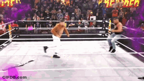 Two Men Are Wrestling In A Wrestling Ring With A Crowd Watching GIF