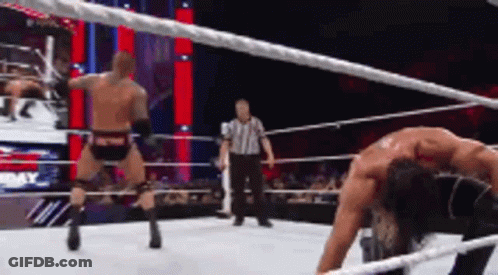 Two Men Are Wrestling In A Wrestling Ring With A Referee In The Background GIF