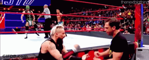 Two Men Are Wrestling In A Wrestling Ring With A Referee Watching . GIF