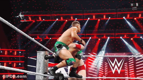 Two Men Are Wrestling In A Wrestling Ring With A W Logo In The Back GIF