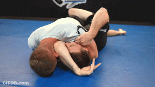 Two Men Are Wrestling On A Blue Mat And One Of Them Is Wearing A Shirt That Says " Ufc " GIF