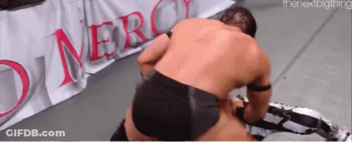 Two Men Are Wrestling On A Wrestling Mat In Front Of A Sign That Says Merci . GIF