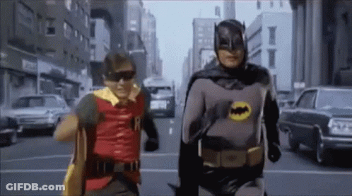 Two Men As Batman And Robin Walking Down Street GIF