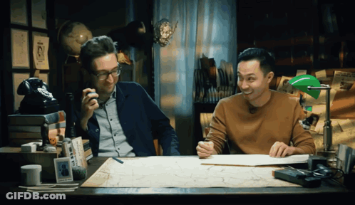 Two Men At Desk With Green Lamp And Map GIF