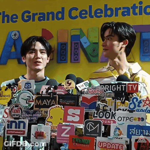 Two Men At Microphones And The Grand Celebratic Sign GIF