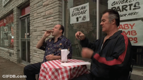 Two Men At Table With Italian Sausage Sign GIF